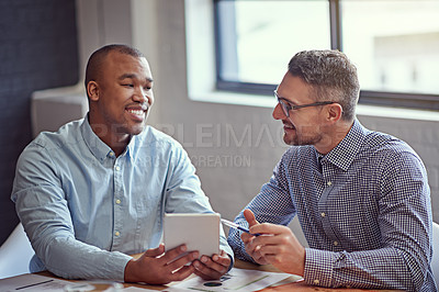 Buy stock photo Shot of two designers working on a digital tablet in an office