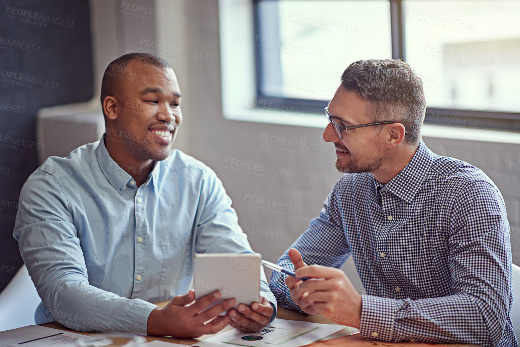 Buy stock photo Shot of two designers working on a digital tablet in an office