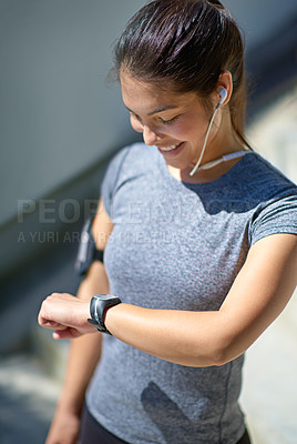 Buy stock photo Happy woman, runner and watch with earphones in tracking performance or fitness in city. Female person checking wristwatch with smile for workout music, exercise or monitoring steps in an urban town