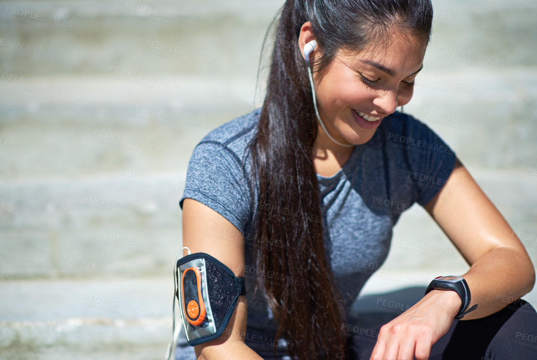 Buy stock photo Shot of a young woman checking her watch while out exercising