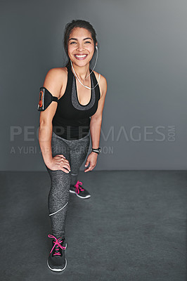 Buy stock photo Shot of a fit young woman stretching her legs against a gray background