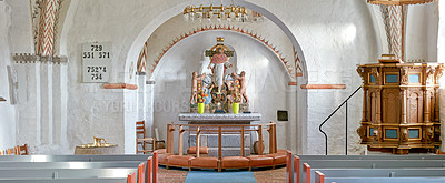 Buy stock photo Interior of a historical church with rows of benches, a pulpit, nave or alter with kneeler cushions and sacred figure of Jesus on a cross. 12th century old Danish National Church in Faarup, Denmark