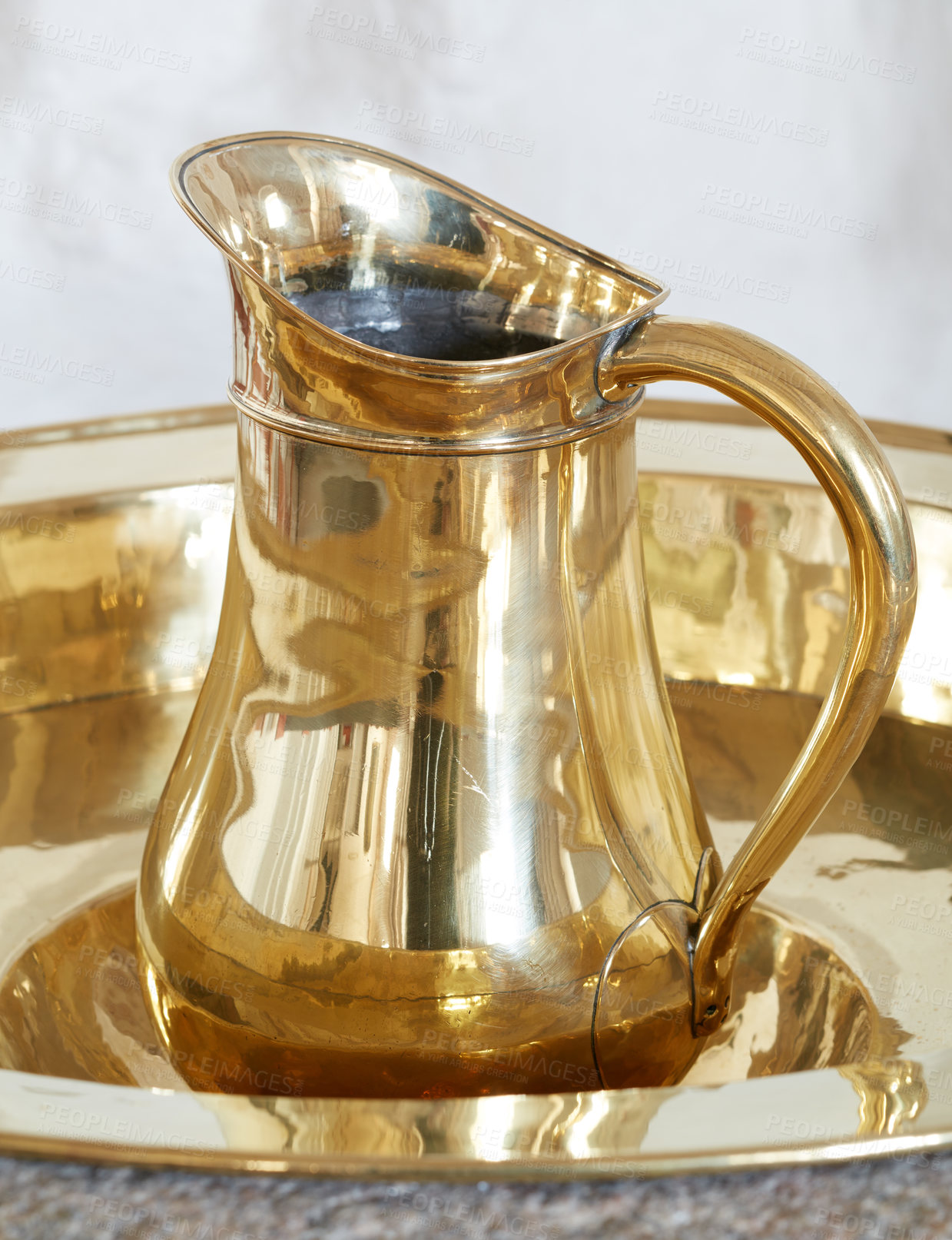 Buy stock photo Bronze baptismal font and jug. Closeup of a shiny tray and pitcher for traditional baptisms in the Danish National Church. One golden brass object and water jug arranged and used to pour holy water