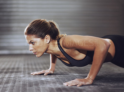 Buy stock photo Cropped shot of a young woman doing push-ups at the gym