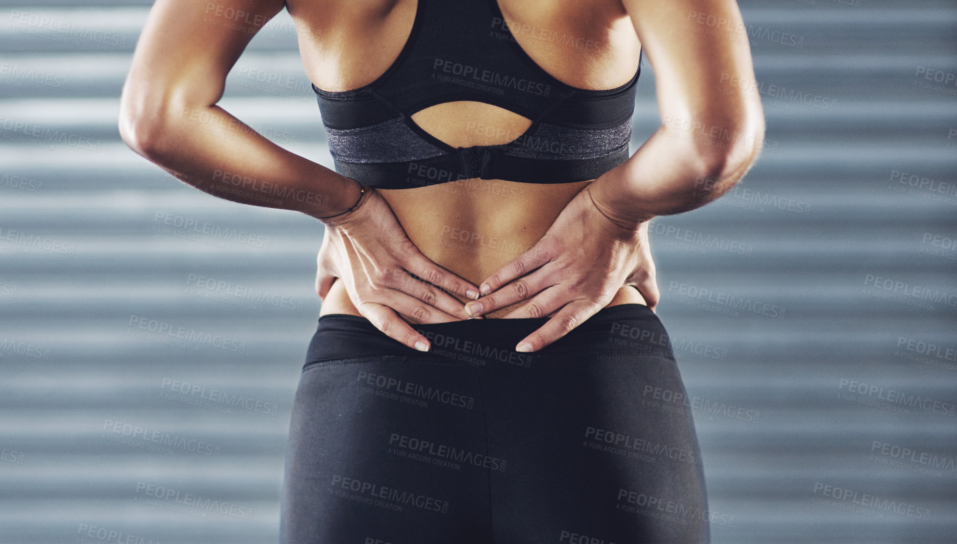 Buy stock photo Shot of a sportswoman with a lower back injury