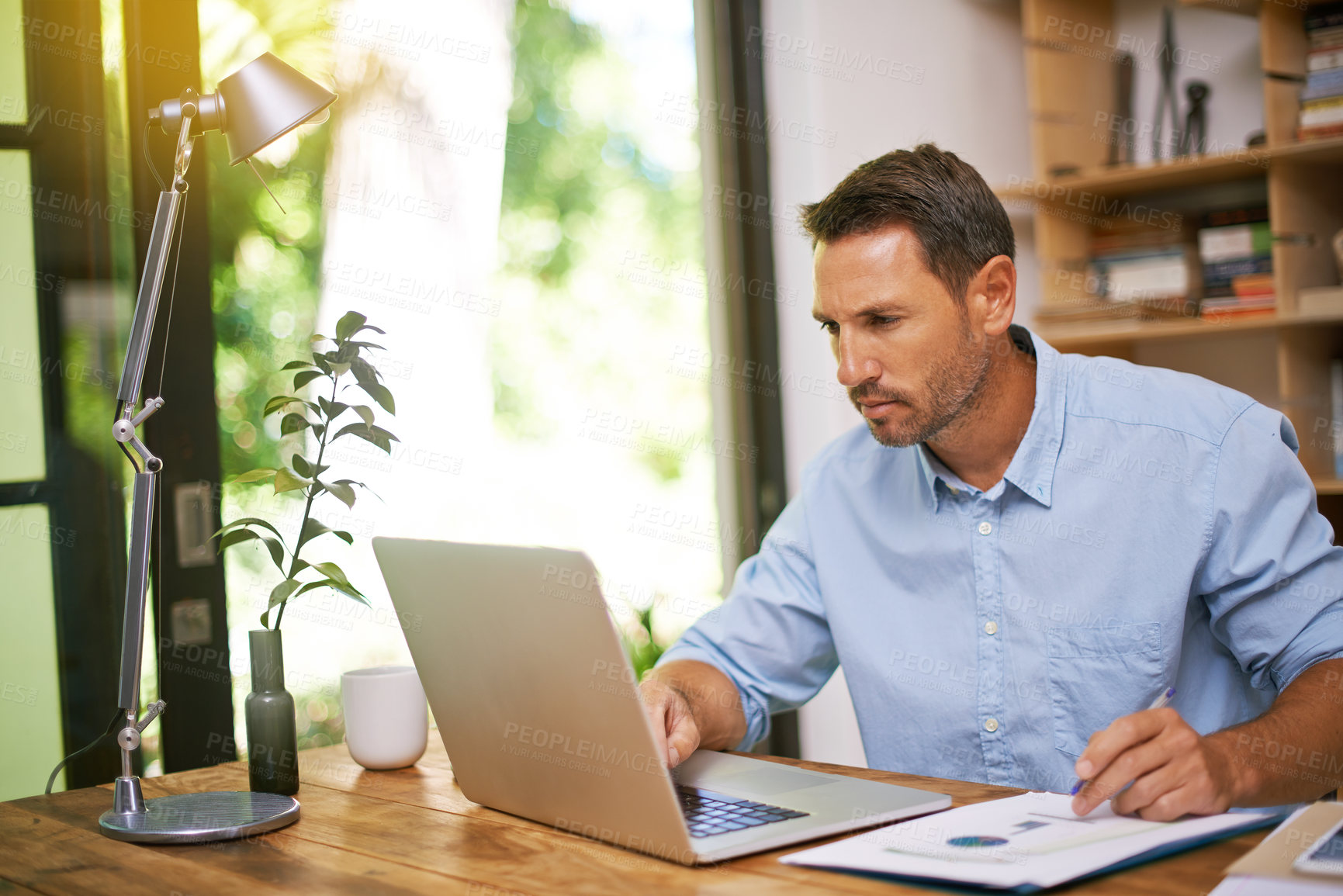 Buy stock photo Man, reading and laptop with documents for remote work from home office with charts, stats or financial review. Person, computer and paperwork with info, insight and feedback for trading in apartment