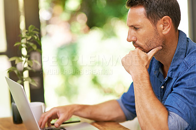Buy stock photo Shot of a man working on his laptop at home