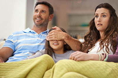 Buy stock photo Shot of a father covering his daughter's eyes while watching a movie at home