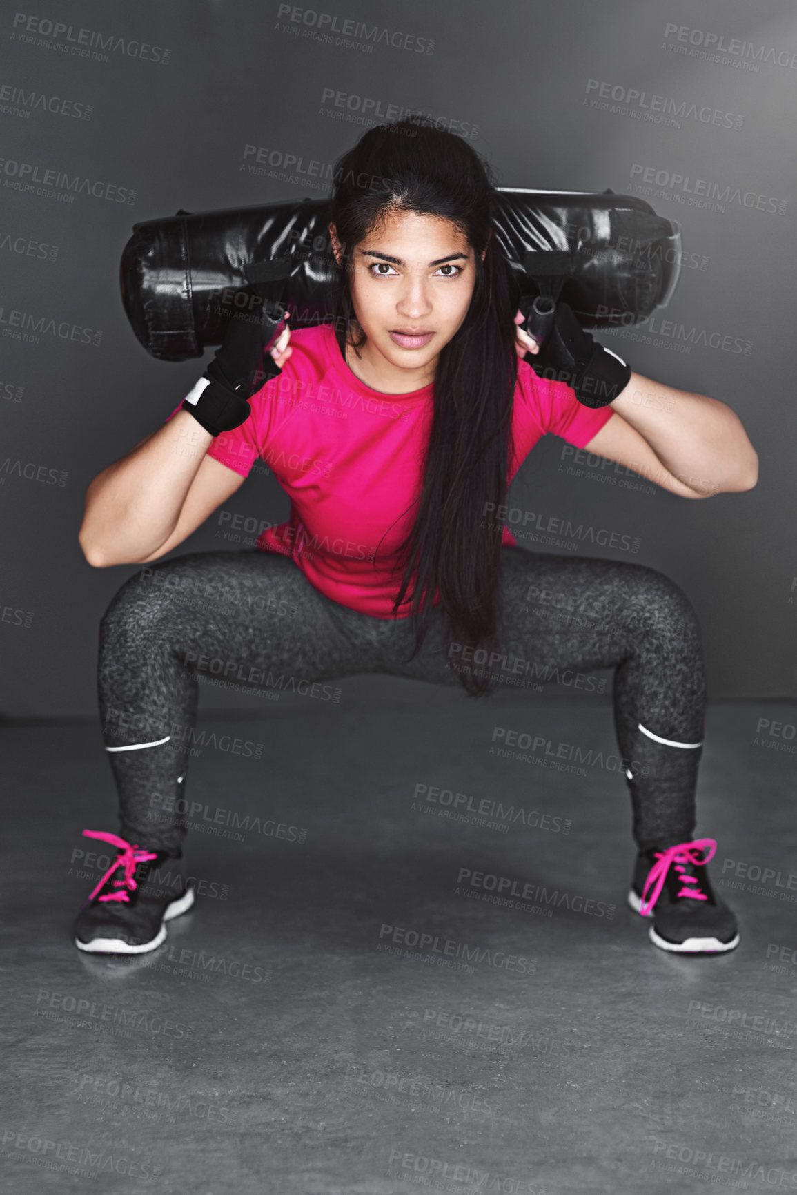 Buy stock photo Studio shot of an attractive young woman working out with dumbbells  against a gray background