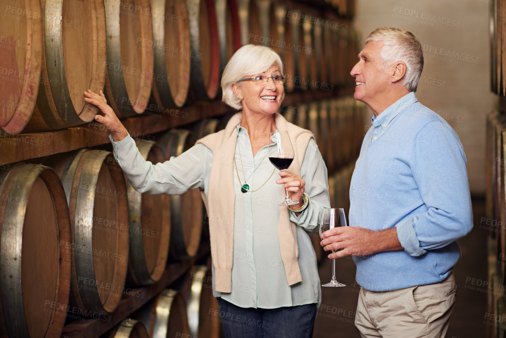Buy stock photo Cropped shot of an affectionate senior couple wine tasting in a cellar