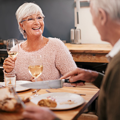 Buy stock photo Senior couple, food and alcohol for love at table, conversation and healthy meal in home for anniversary. People, bonding and eating together on weekend, relax and speaking on romantic dinner date