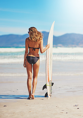 Buy stock photo Rearview shot of a young surfer standing on the beach