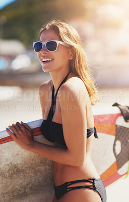 Buy stock photo Shot of a young surfer walking on the beach with her surfboard