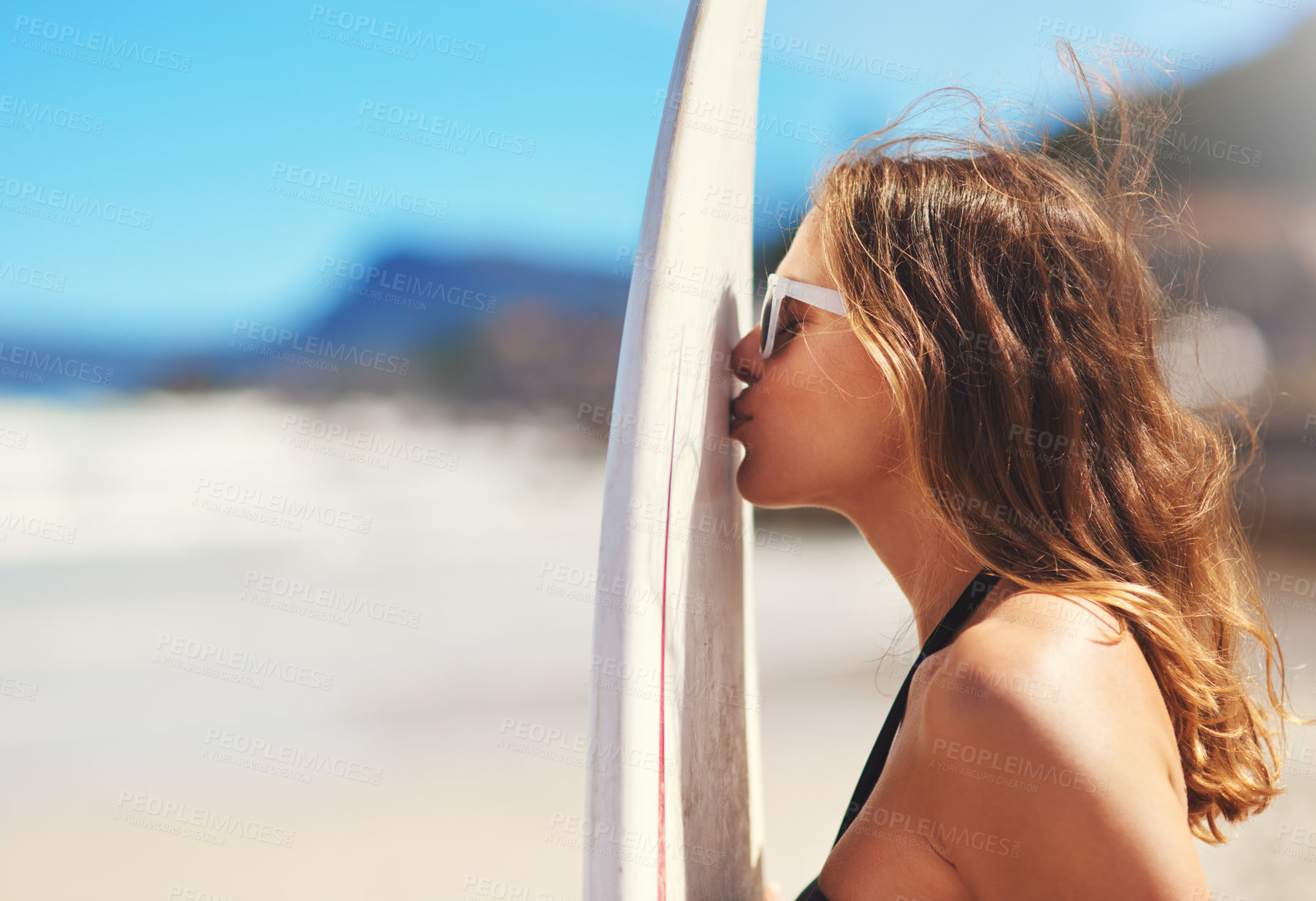 Buy stock photo Shot of a young surfer kissing her surfboard on the beach