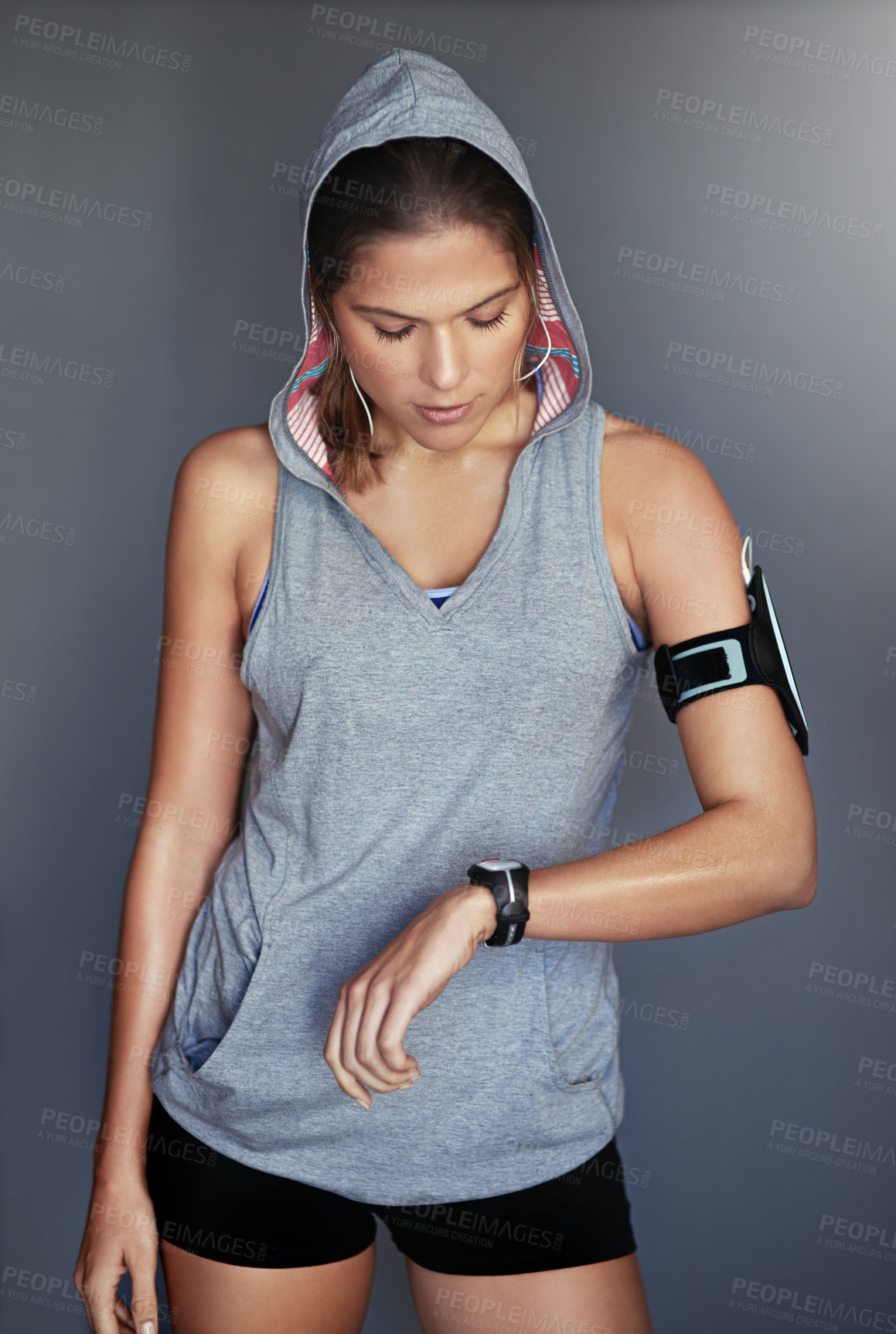 Buy stock photo Woman, athlete and watch for exercise time in studio or timing for running routine, progress or grey background. Female person, hand and arm pouch with earphones or music workout, fitness or tracker