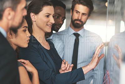 Buy stock photo Shot of a group of businesspeople looking over plans on a whiteboard