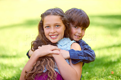 Buy stock photo Cropped shot of a young boy embracing his sister while sitting on the grass outside