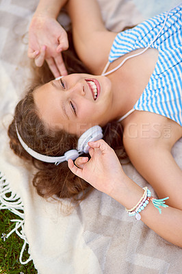 Buy stock photo High angle shot of a young girl listening to music while lying on a blanket outside