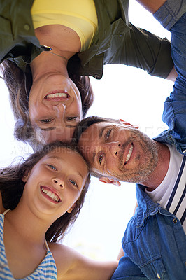 Buy stock photo Low angle shot of a young family standing in a huddle outside