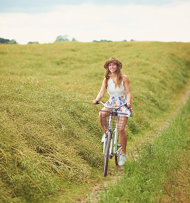 Buy stock photo Shot of a young woman cycling through the countryside