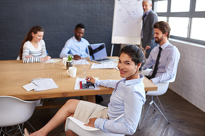 Buy stock photo Portrait of a young businesswoman sitting around a table with her colleagues in the boardroom