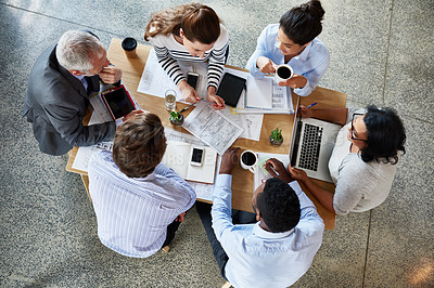 Buy stock photo High angle shot of a group of coworkers sitting around a table in the boardroom