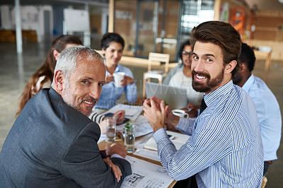 Buy stock photo Portrait of two businessmen sitting around a table with their colleagues in the boardroom