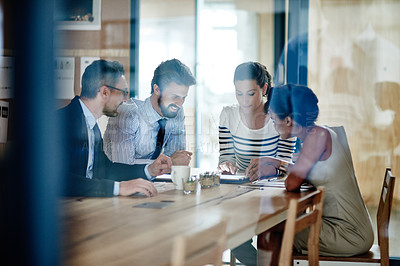 Buy stock photo Through the glass shot of a group of colleagues working together in an office