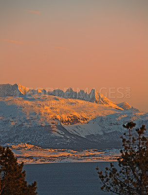 Buy stock photo Landscape view of snow covered land against a sunset background with copyspace.  Bare frosty lands and trees on a field with mountains and hills in the background. A snow blanket covering the ground 