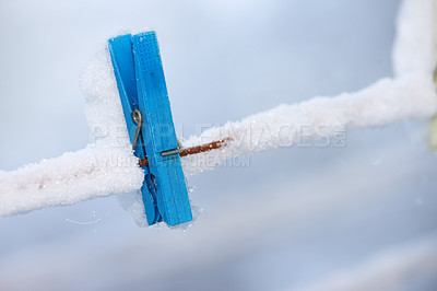 Buy stock photo One frozen blue wooden peg covered in snow on a line. An old wooden clothespin on a washing line in an icy garden. Old fashioned tool for hanging freshly cleaned laundry on a dewy cold winter day 