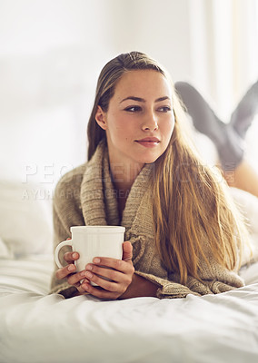 Buy stock photo Shot of a young woman drinking a warm beverage at home