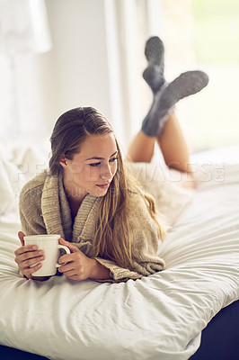 Buy stock photo Shot of a young woman drinking a warm beverage at home