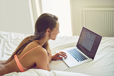 Buy stock photo Shot of a young woman using a laptop in her underwear during the morning