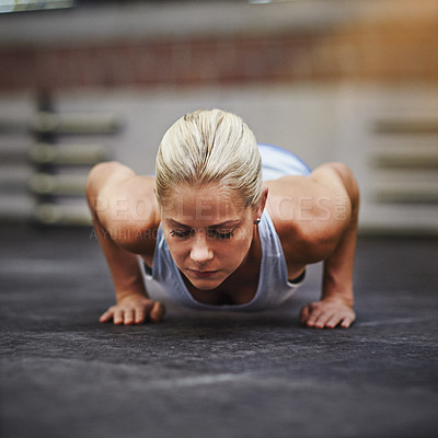 Buy stock photo Shot of a young woman doing pushups in a gym