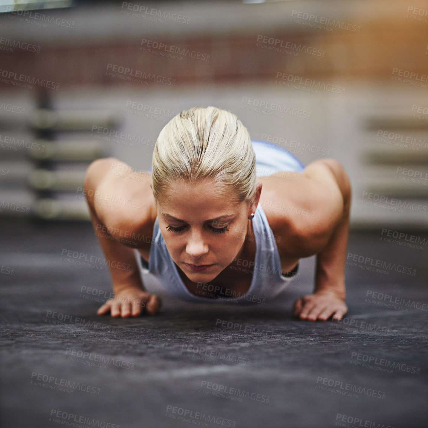 Buy stock photo Shot of a young woman doing pushups in a gym