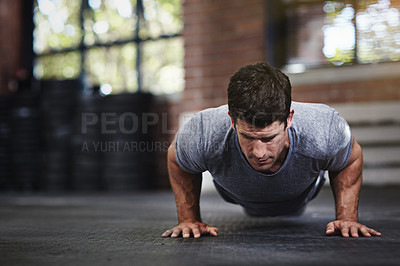 Buy stock photo Shot of a young man doing pushups in a gym