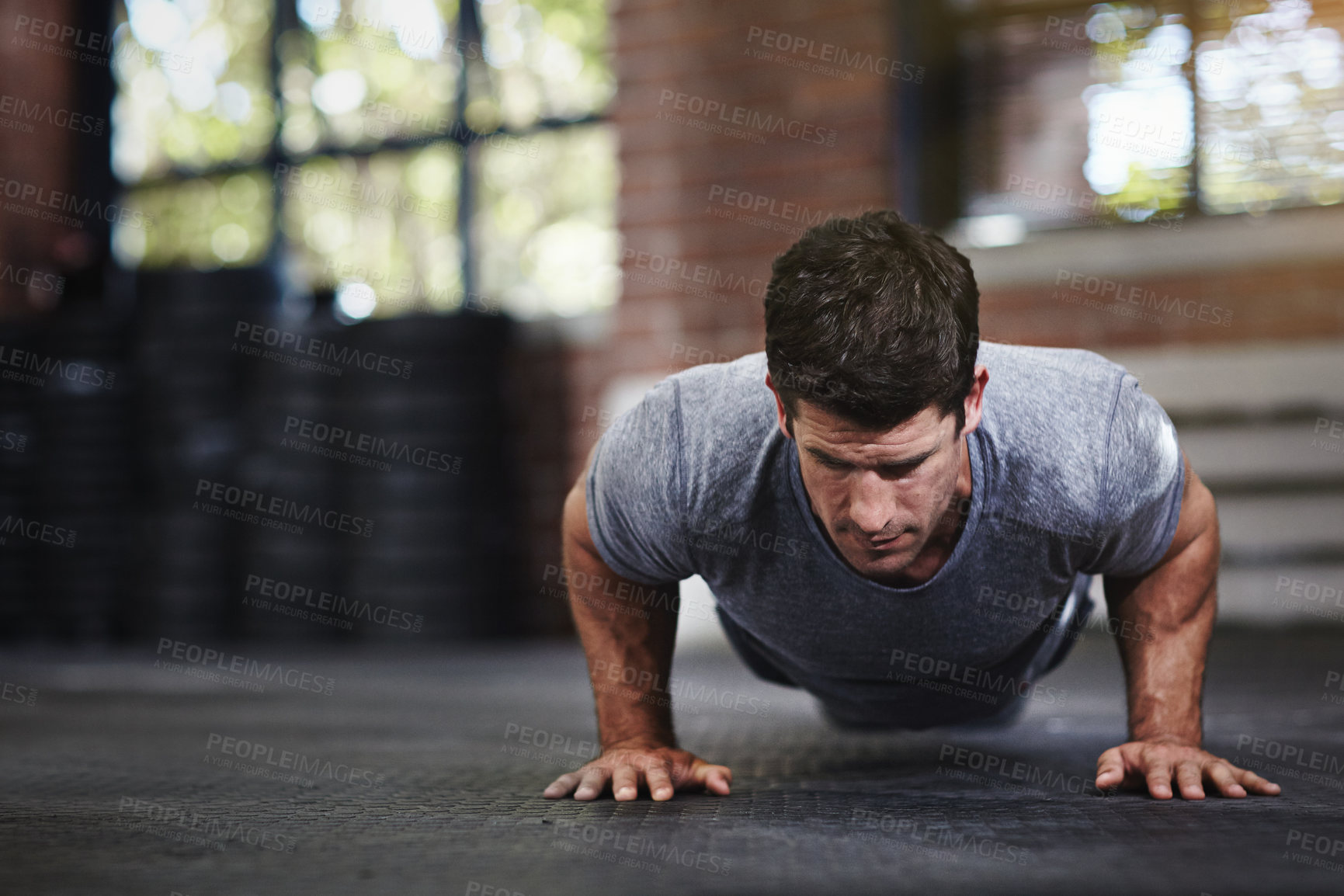 Buy stock photo Shot of a young man doing pushups in a gym