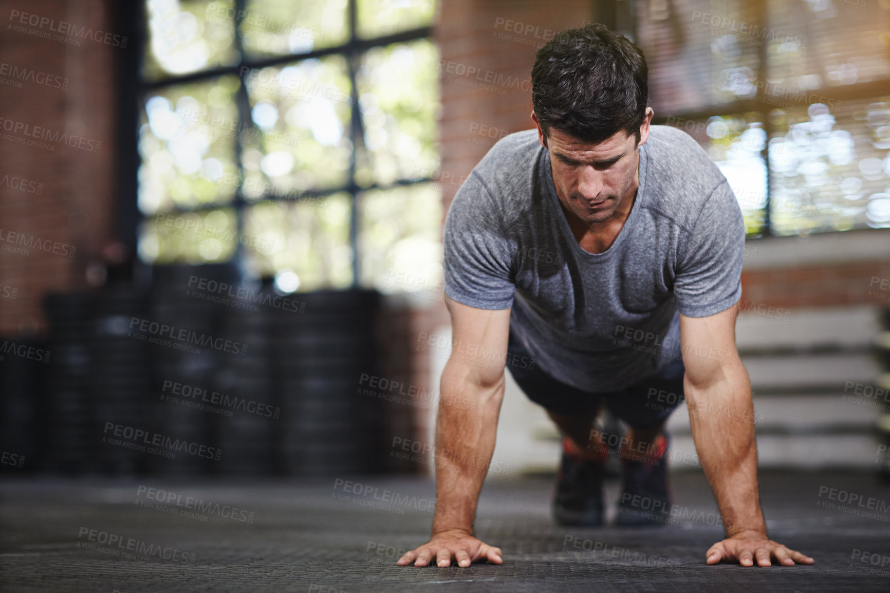 Buy stock photo Shot of a young man doing pushups in a gym