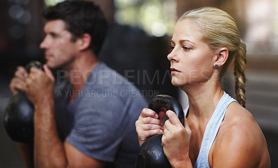 Buy stock photo Shot of two people working out with kettlebells in a gym