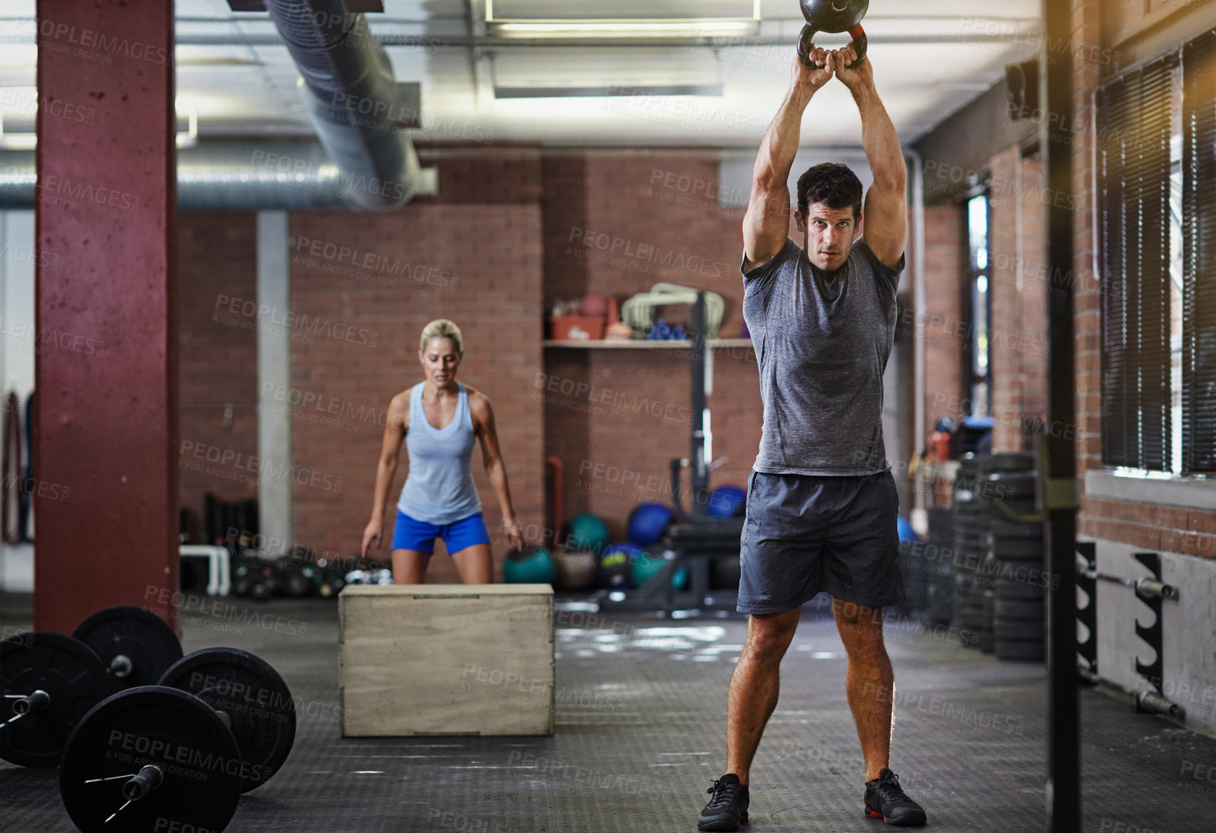 Buy stock photo Shot of two people working out with kettlebells in a gym