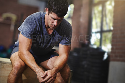 Buy stock photo Shot of a young man taking a break from working out in a gym