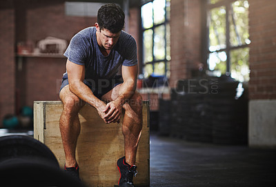 Buy stock photo Shot of a young man taking a break from working out in a gym