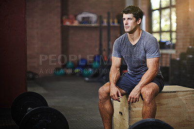 Buy stock photo Shot of a young man taking a break from working out in a gym