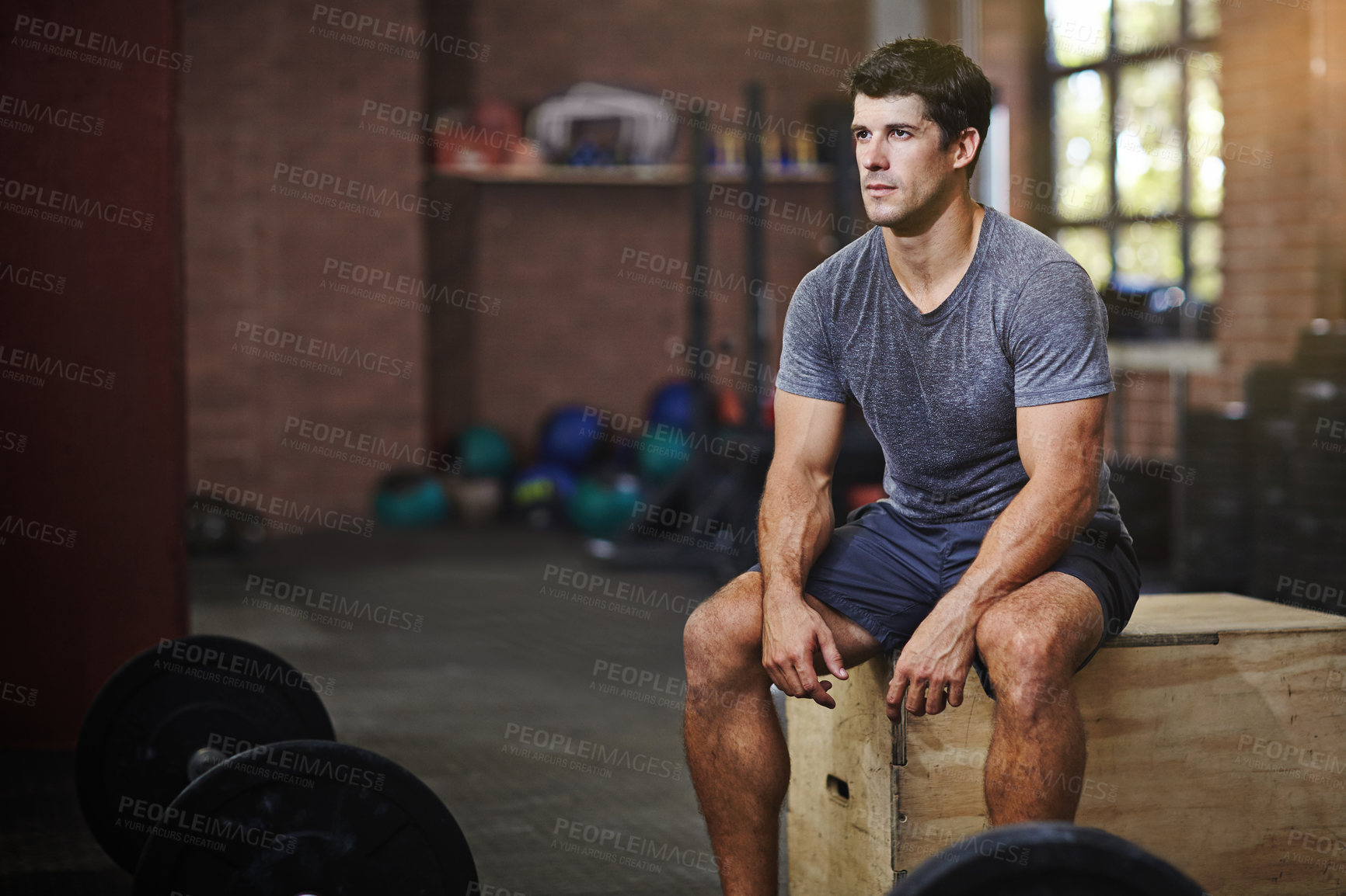 Buy stock photo Shot of a young man taking a break from working out in a gym