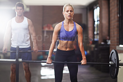 Buy stock photo Shot of two people lifting weights in a gym