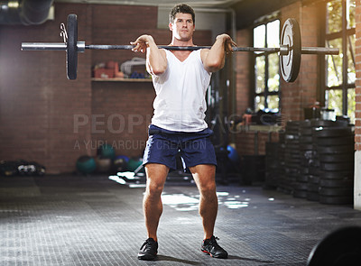 Buy stock photo Shot of a young man lifting weights in a gym