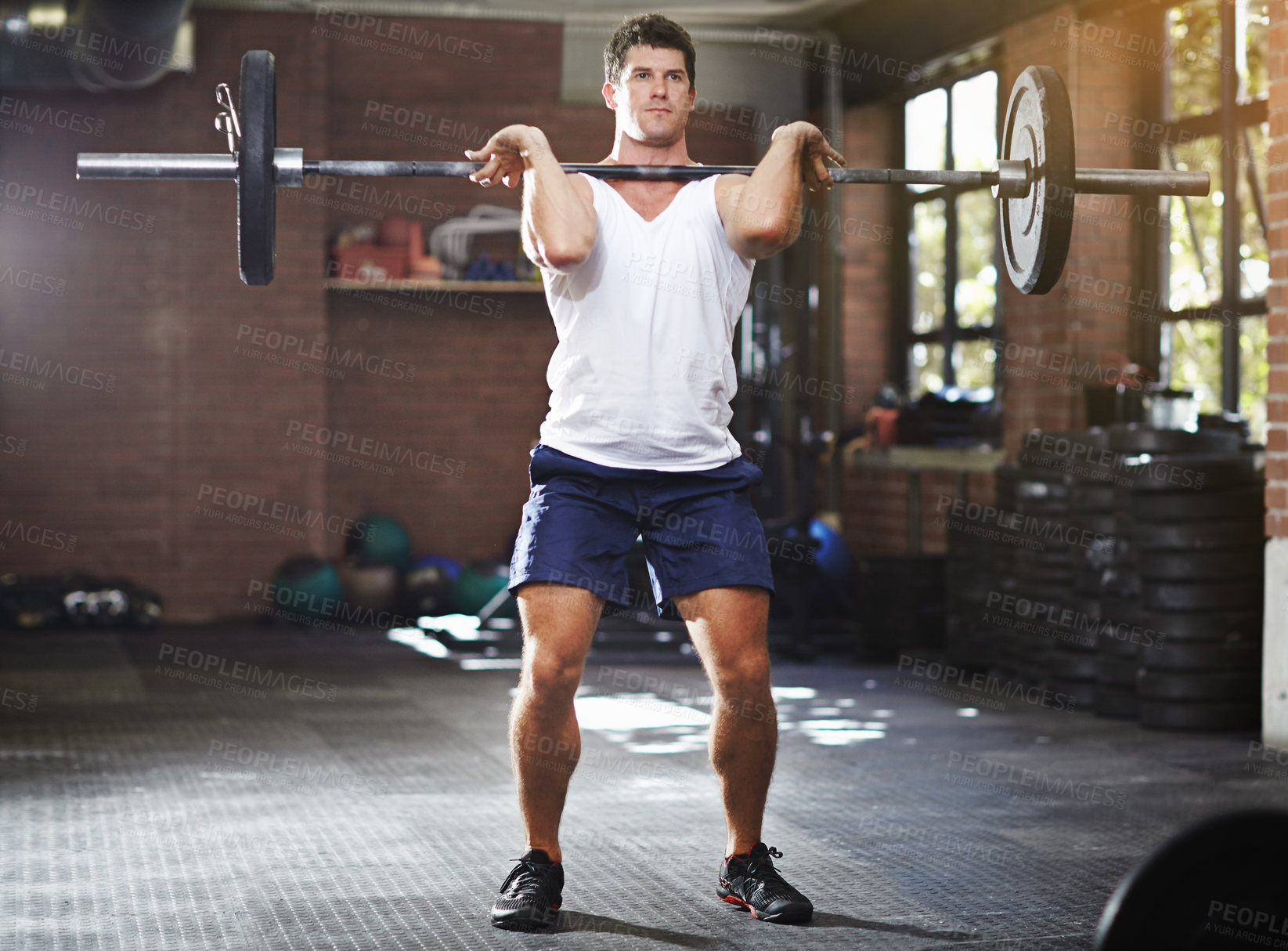 Buy stock photo Shot of a young man lifting weights in a gym