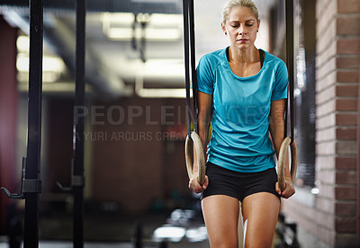 Buy stock photo Shot of a young woman working out with gymnastics rings in a gym