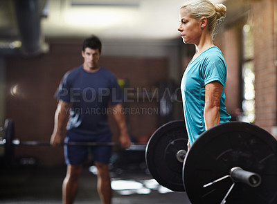 Buy stock photo Shot of two people lifting weights in a gym