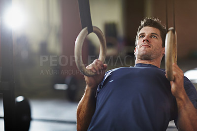 Buy stock photo Shot of a young man working out with gymnastics rings in a gym